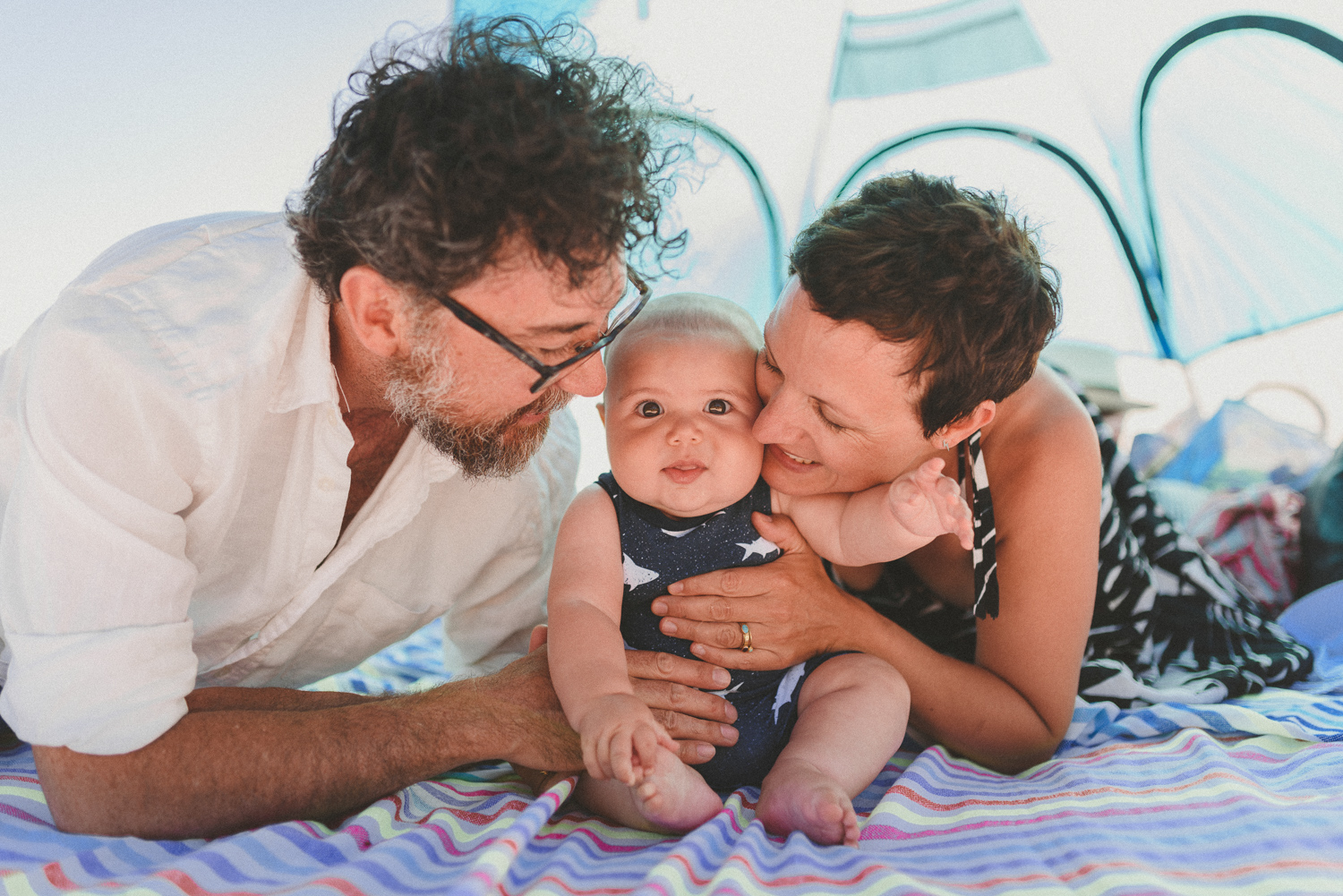 mom, dad & baby snuggling in a beach tent on hornby island