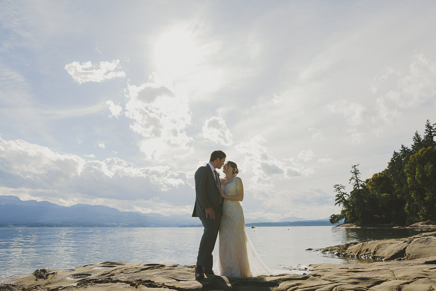 overbury resort thetis island wedding-couple kissing with the ocean & big sunset sky behind them