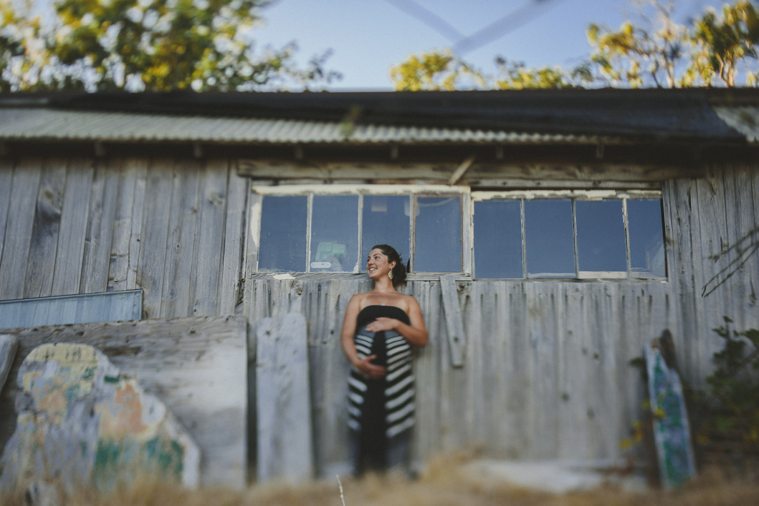 young pregnant woman leaning against an old cedar sided workshop-hornby island lifestyle maternity session
