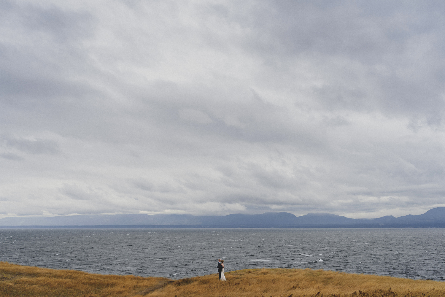 wide angle picture of bride and groom next to ocean on hornby island wedding day