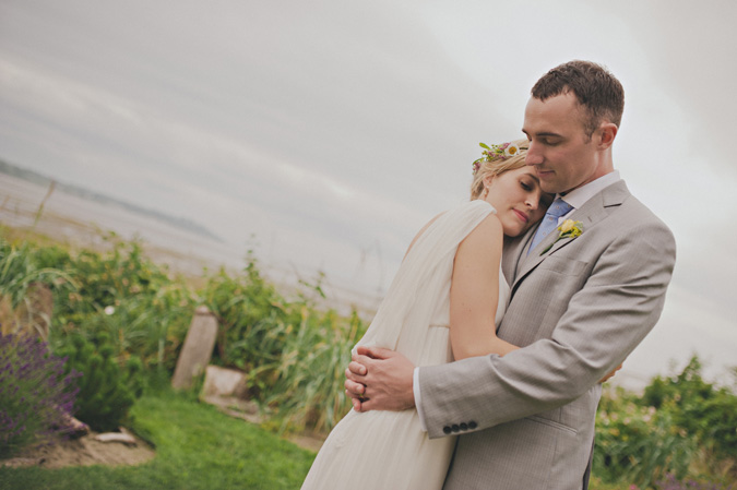 bride and groom hug next to a beach