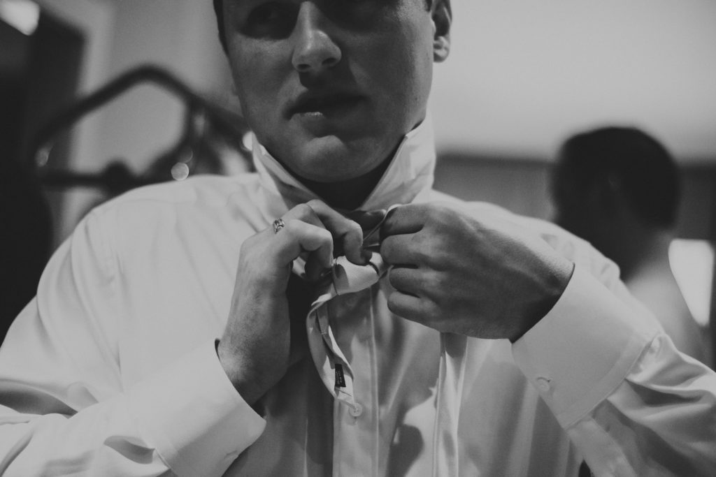 close-up of a groom tying his tie