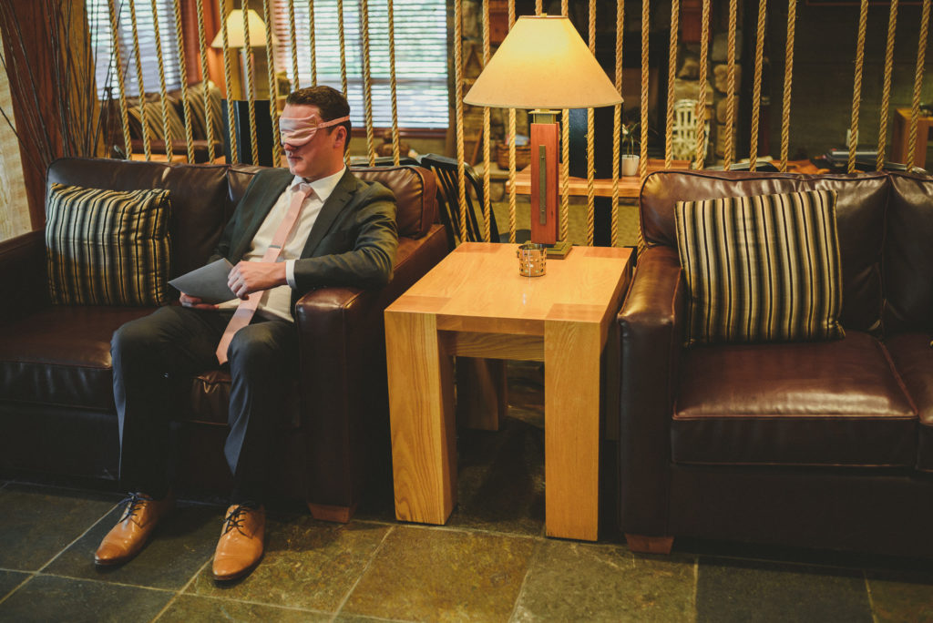 groom waiting in a hotel lobby blindfolded