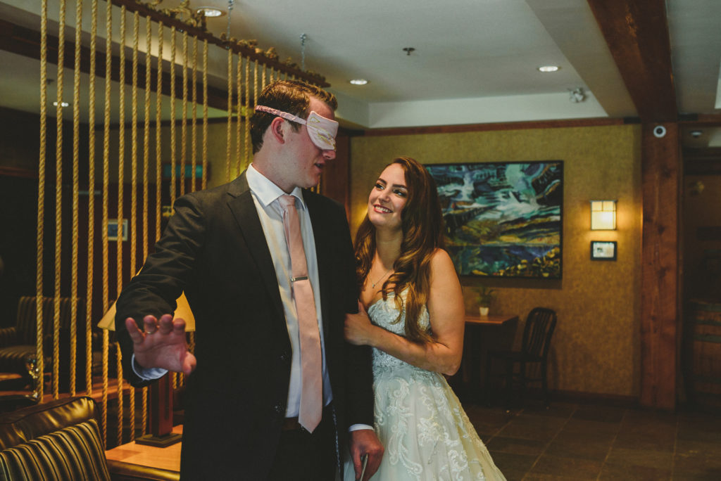bride hugging her blindfolded groom in a hotel lobby
