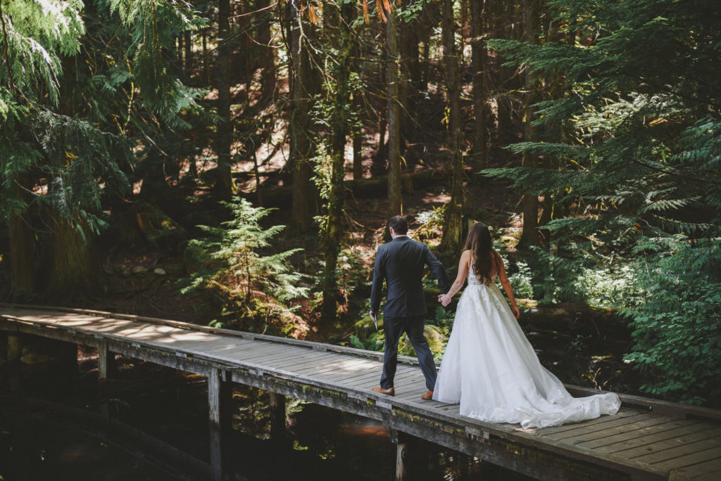groom leading his bride into the forest along a boardwalk
