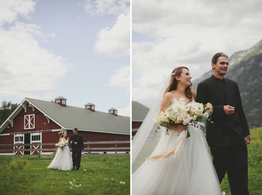 bride & her father walking up the aisle with a large red barn behind them