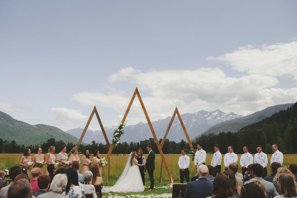 bride & groom & wedding party at their alter with a field & mountains behind them