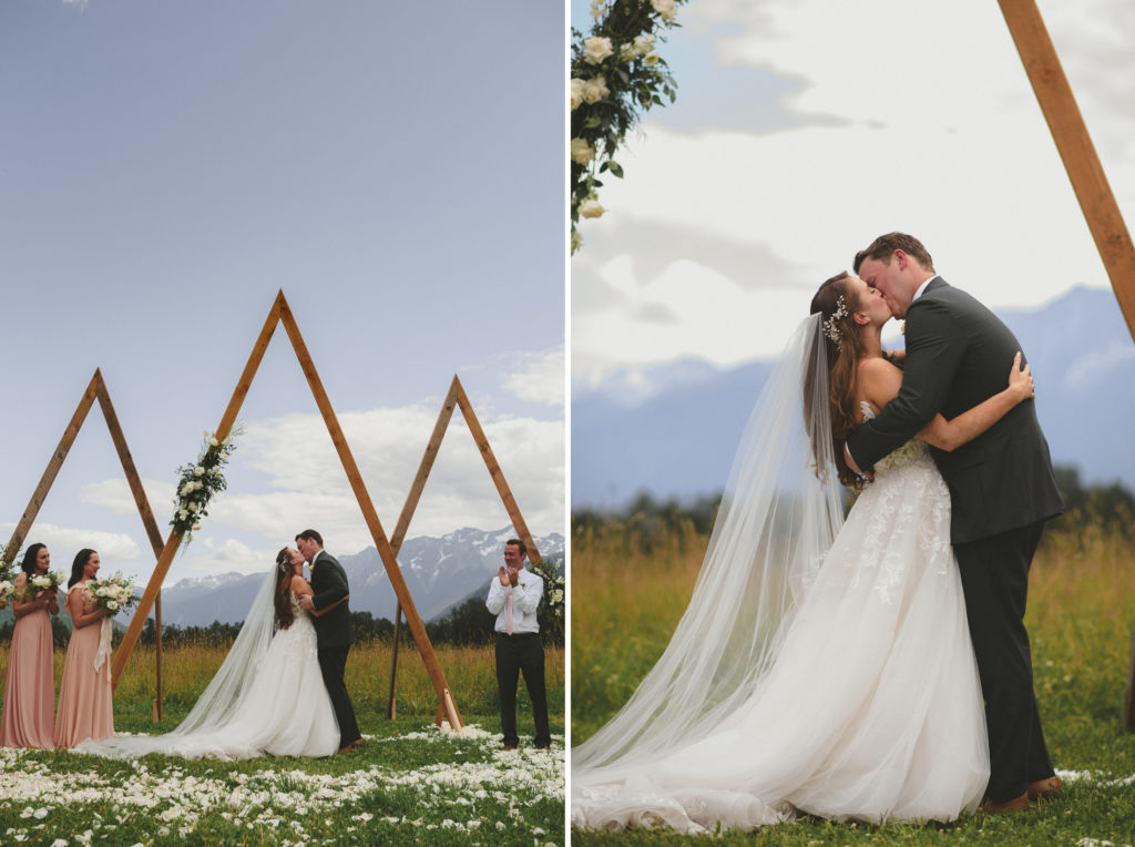 bridkkissing at their alter with a field & mountains behind them