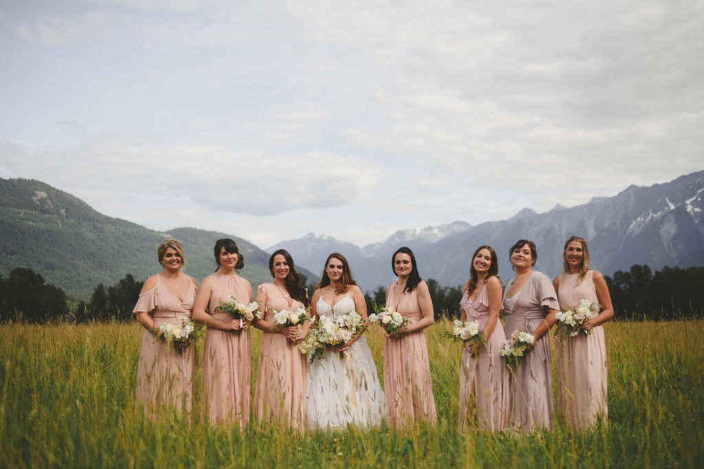 bride & bridesmaids in a field with mountains behind them