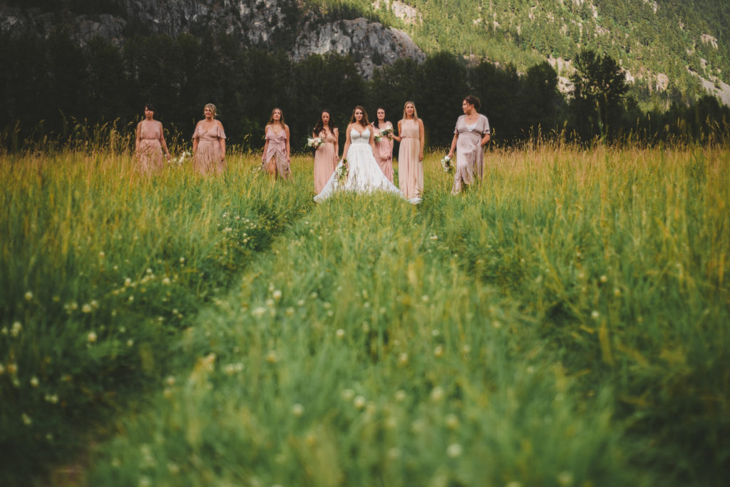 bride & bridesmaids in a field with mountains behind them