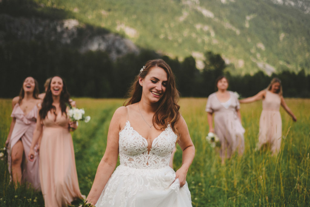 bride & bridesmaids walking in a field with mountains behind them