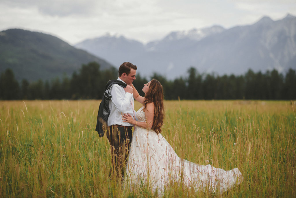 bride & groom in a field with the mountains behind them