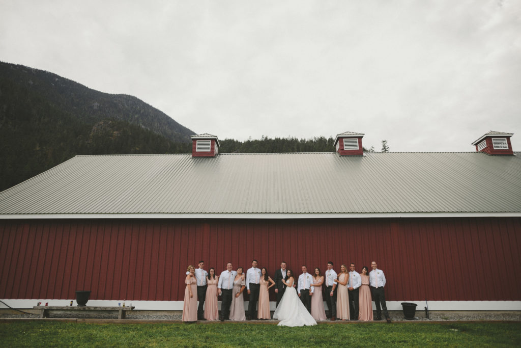 wedding party standing against a large red barn