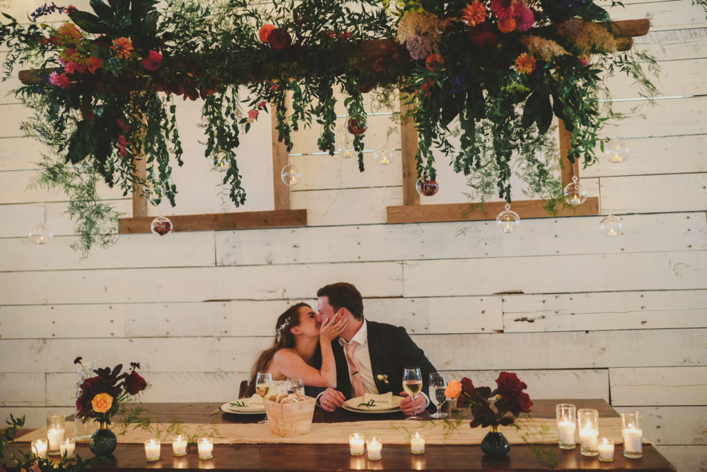 bride & groom kissing at their beautifully decorated head table