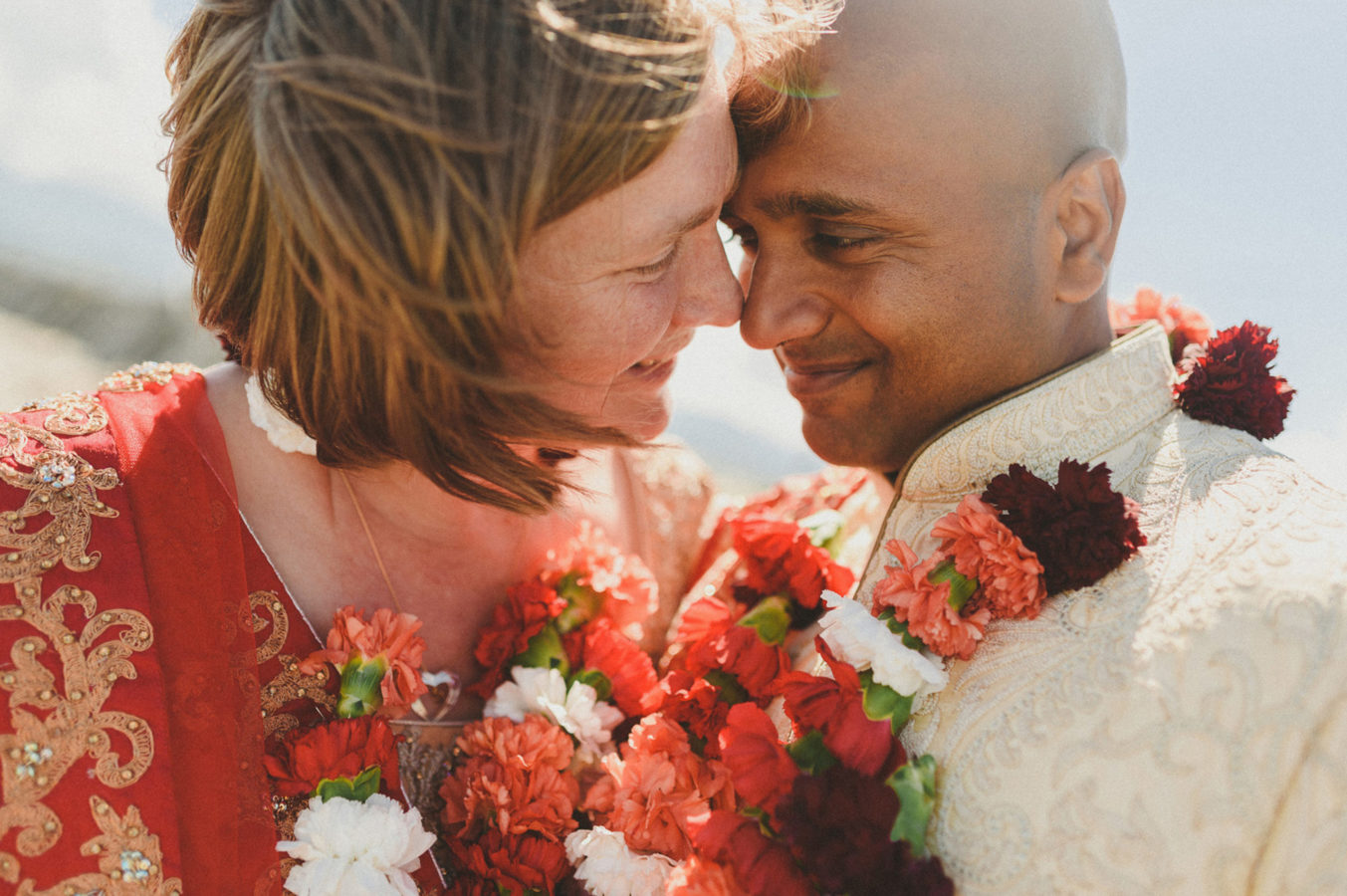 close up of mixed race couple with colourful garlands on their wedding day