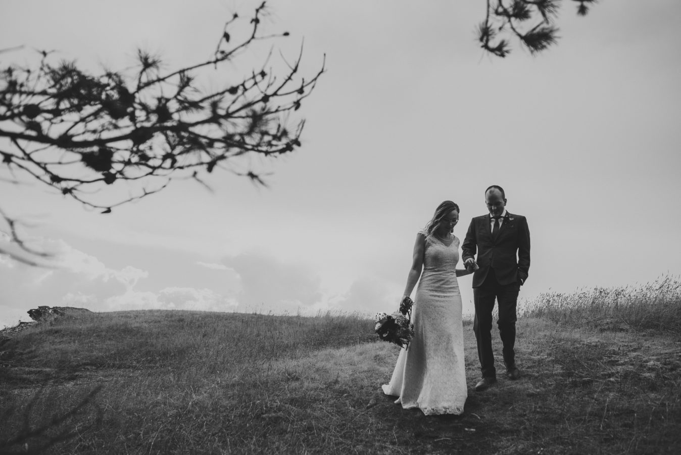 bride and groom holding hands as she leads him into the forest