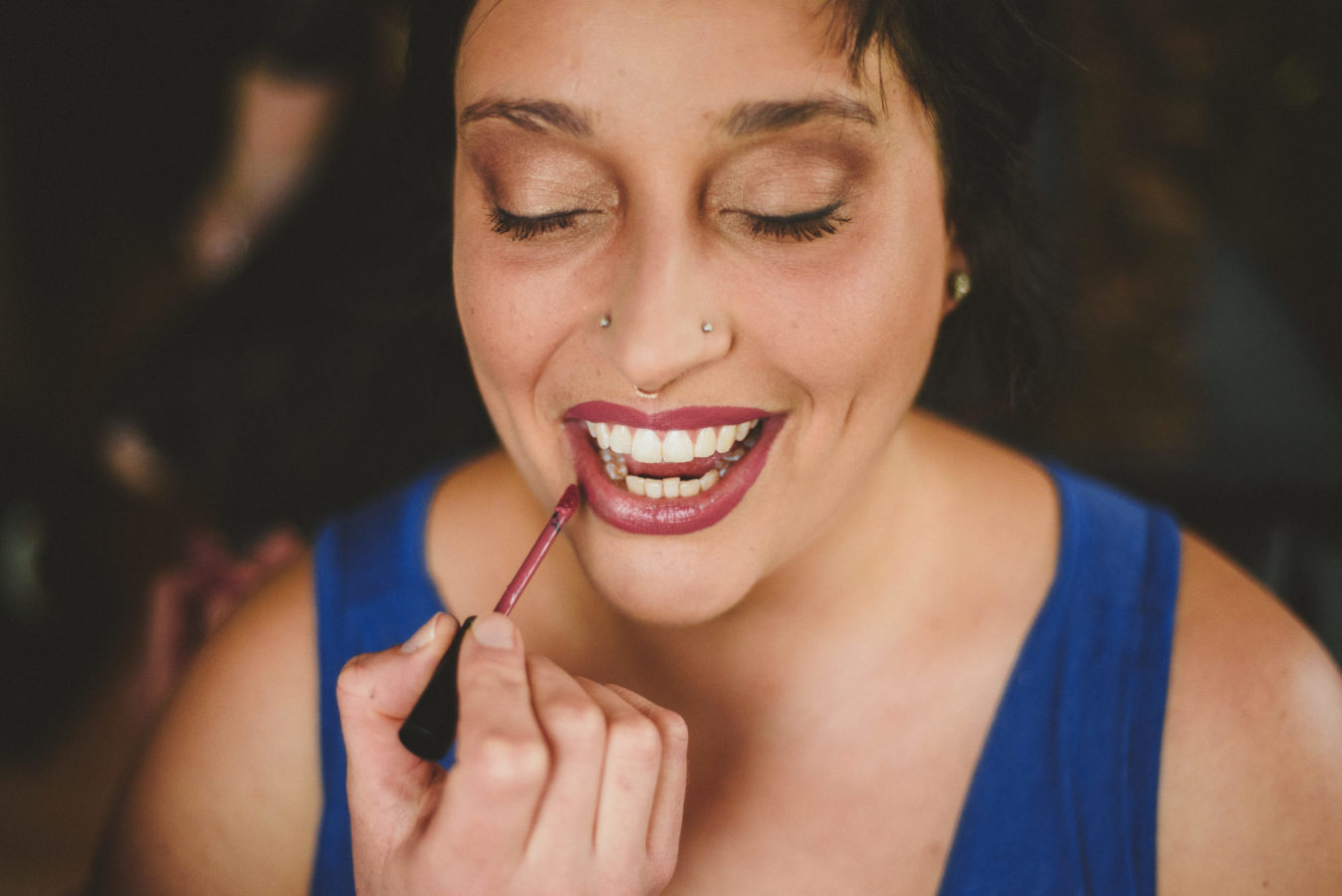 close up of a bride smiling while getting her lipstick applied on her wedding day