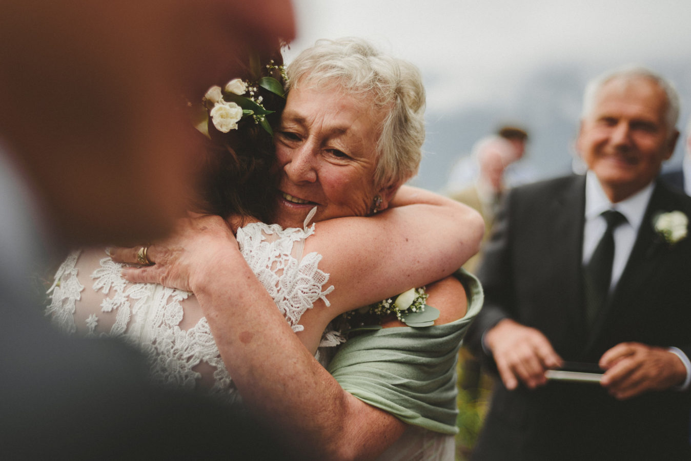 face of an older woman emotionally smiling as she hugs a bride on her wedding day