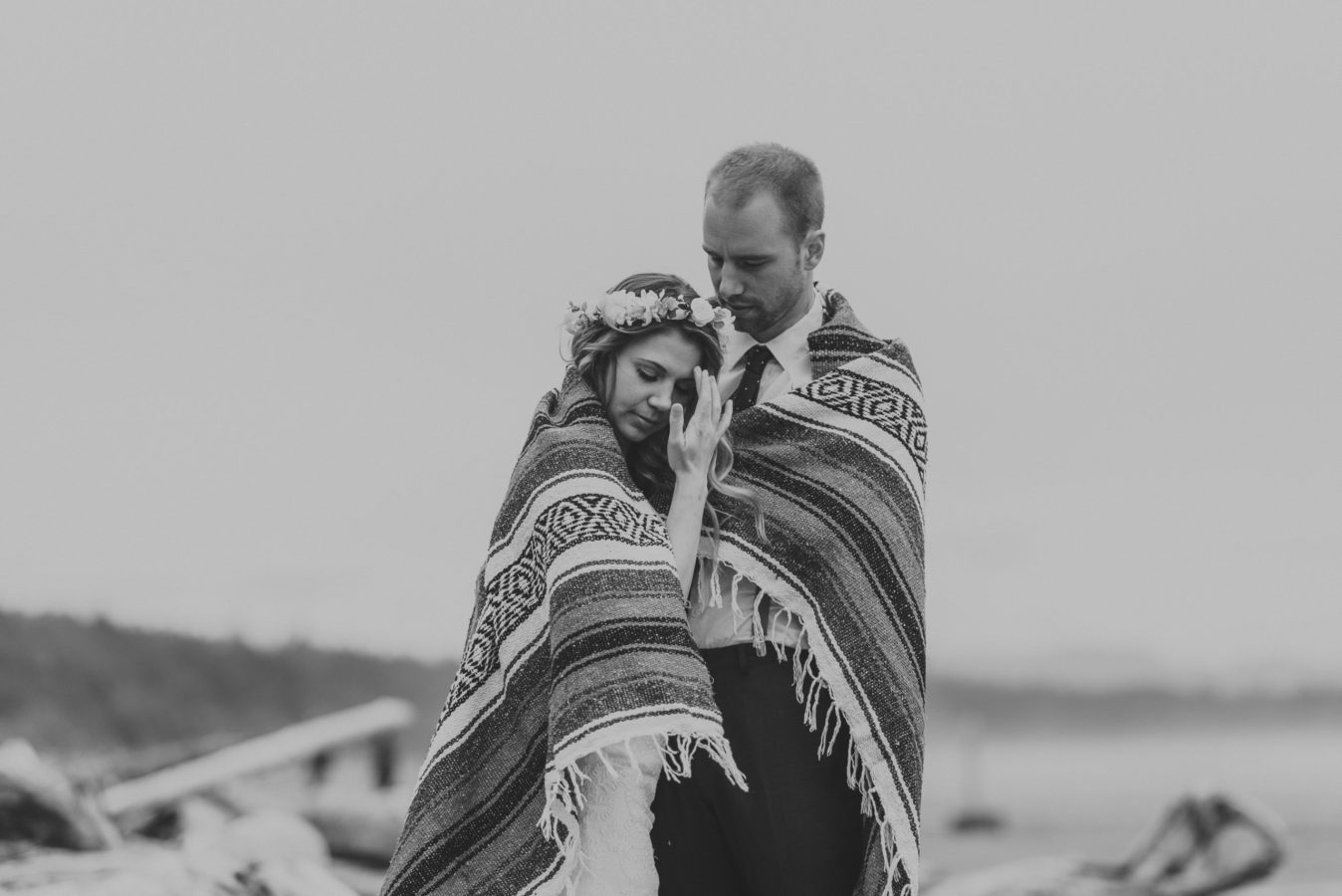 bride and groom wrapped in a blanket standing on the beach in tofino