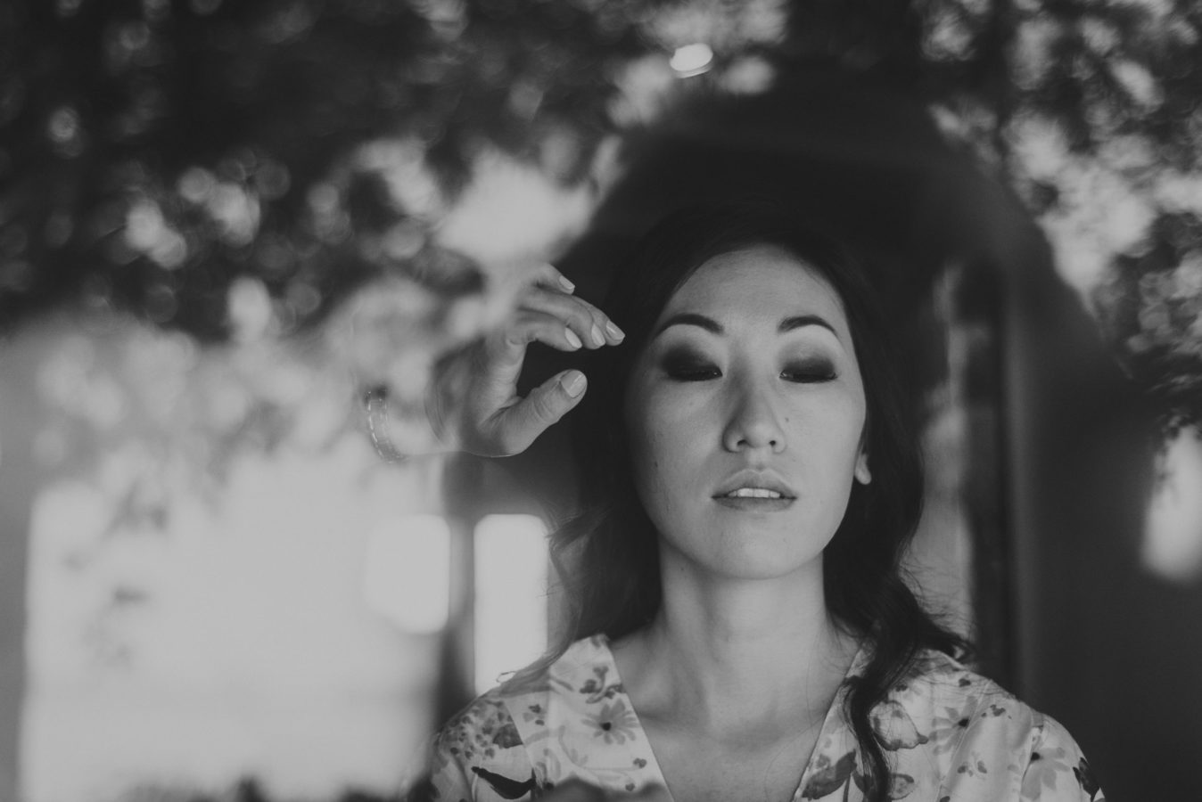 photo taken through a window looking in on a beautiful woman getting her make up done on her wedding day