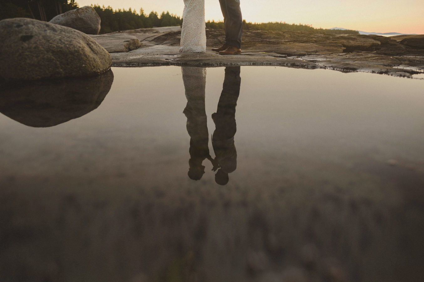reflection of bride and groom in still water in a tidal pool