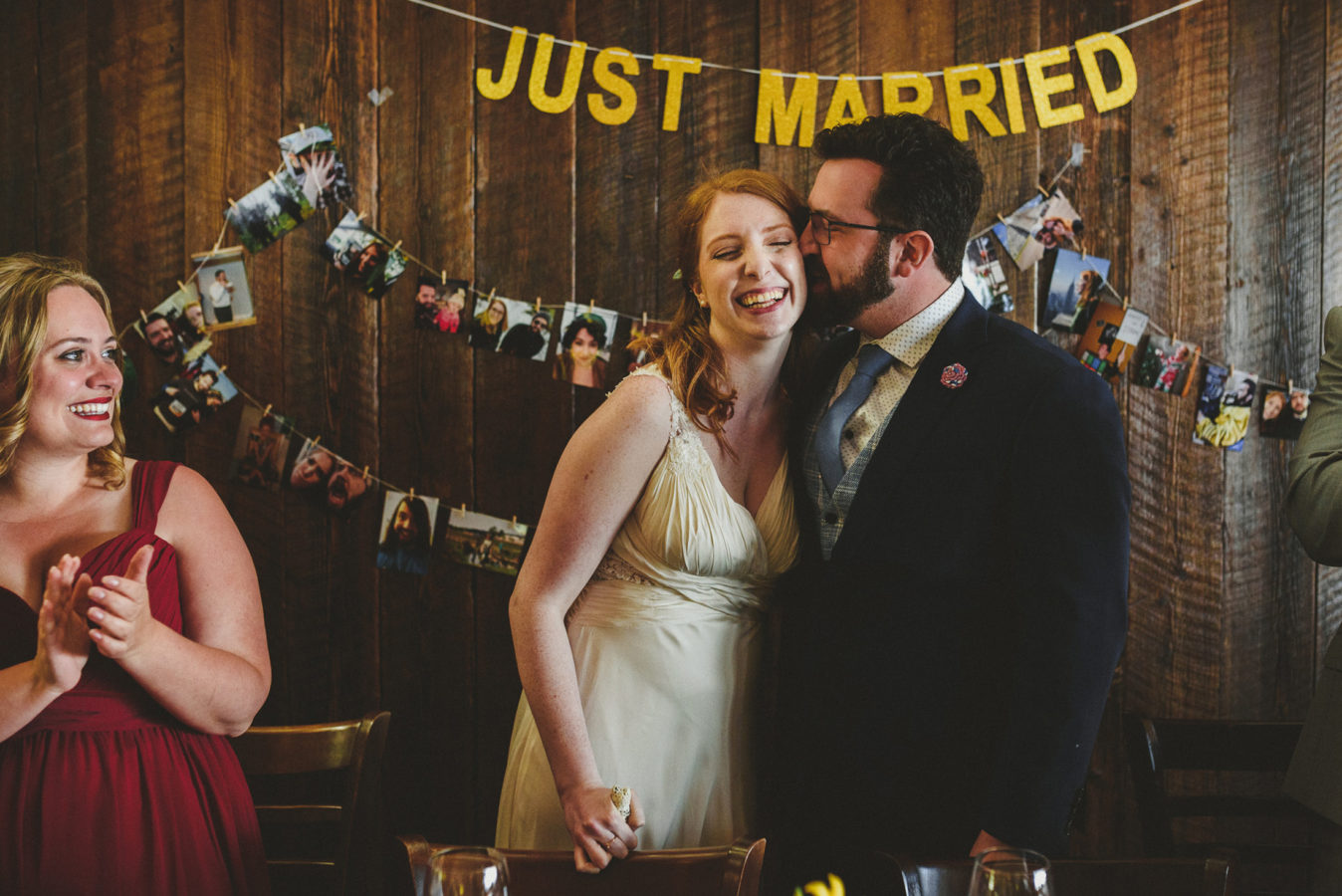 groom kissing his bride at a reception with just married sign behind them