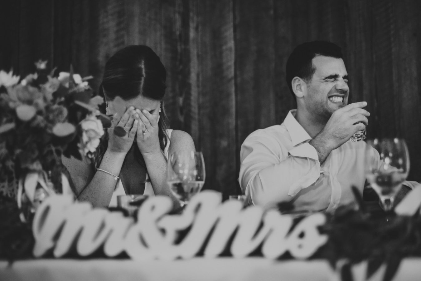 close up sign of mr & mrs with bride and groom laughing in the background