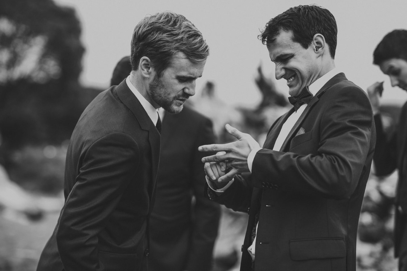 groom trying to pull off his wedding ring to show his friend but it's stuck