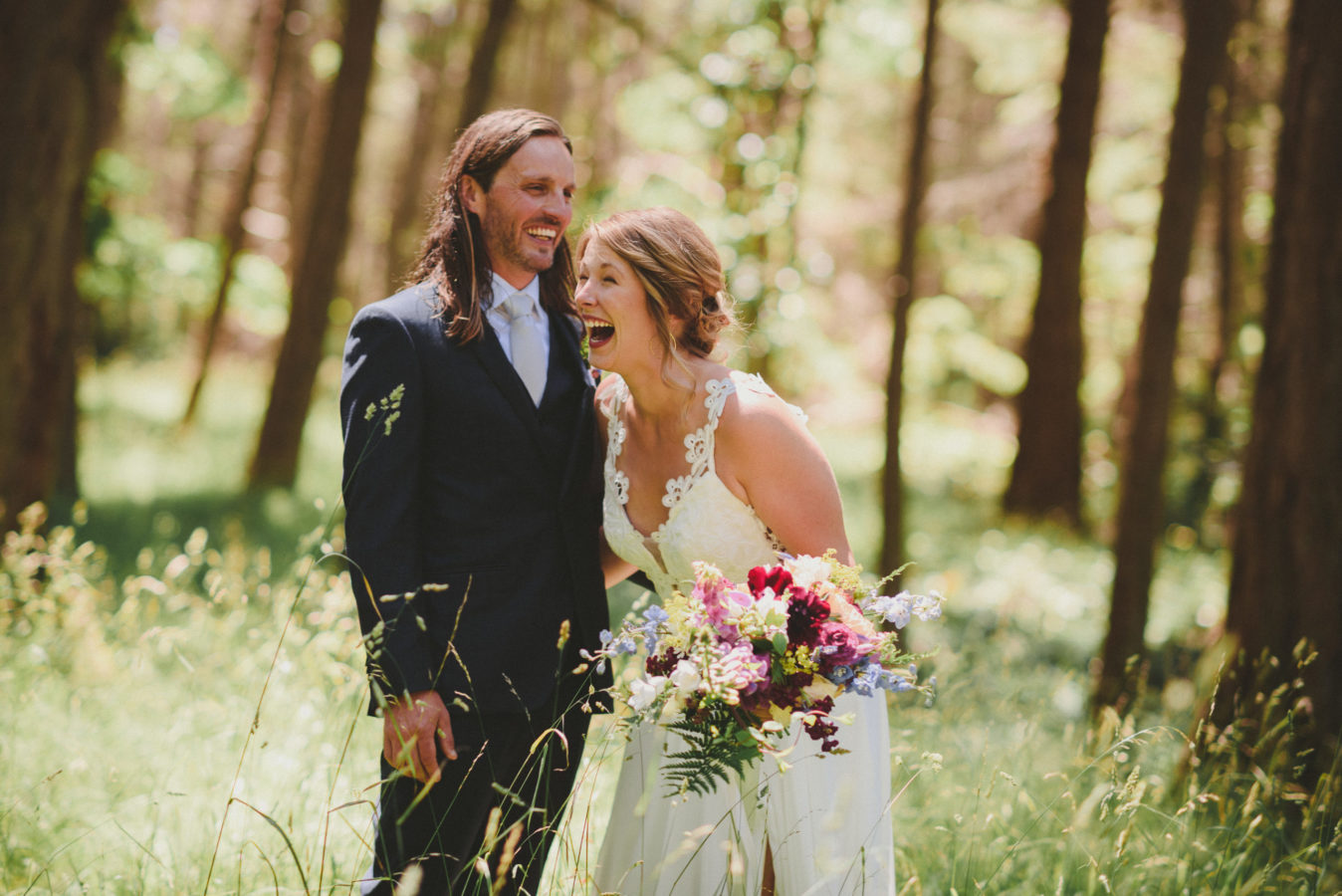 bride and groom laughing in the forest on their wedding day