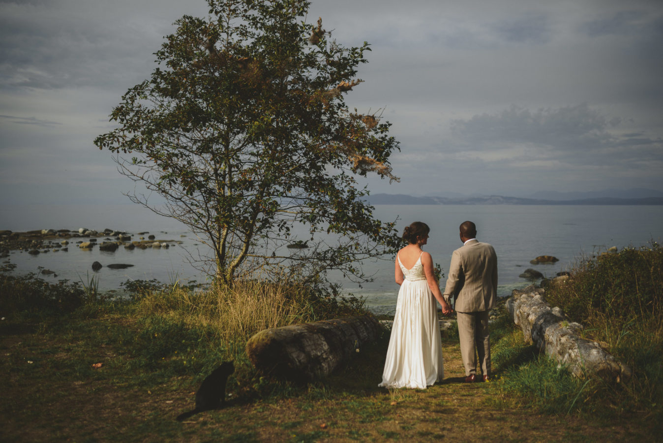 mixed race bride and groom looking out at the ocean on their wedding day