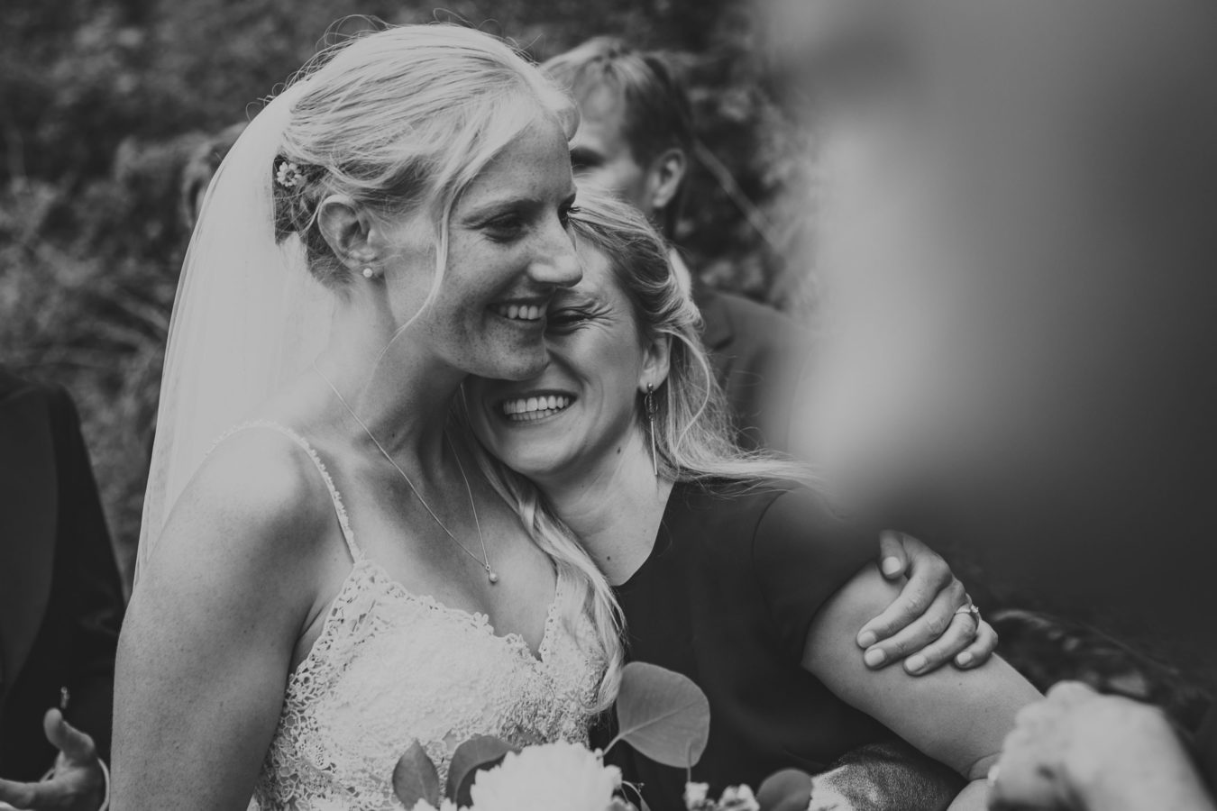 bride embracing a friend both smiling on her wedding day