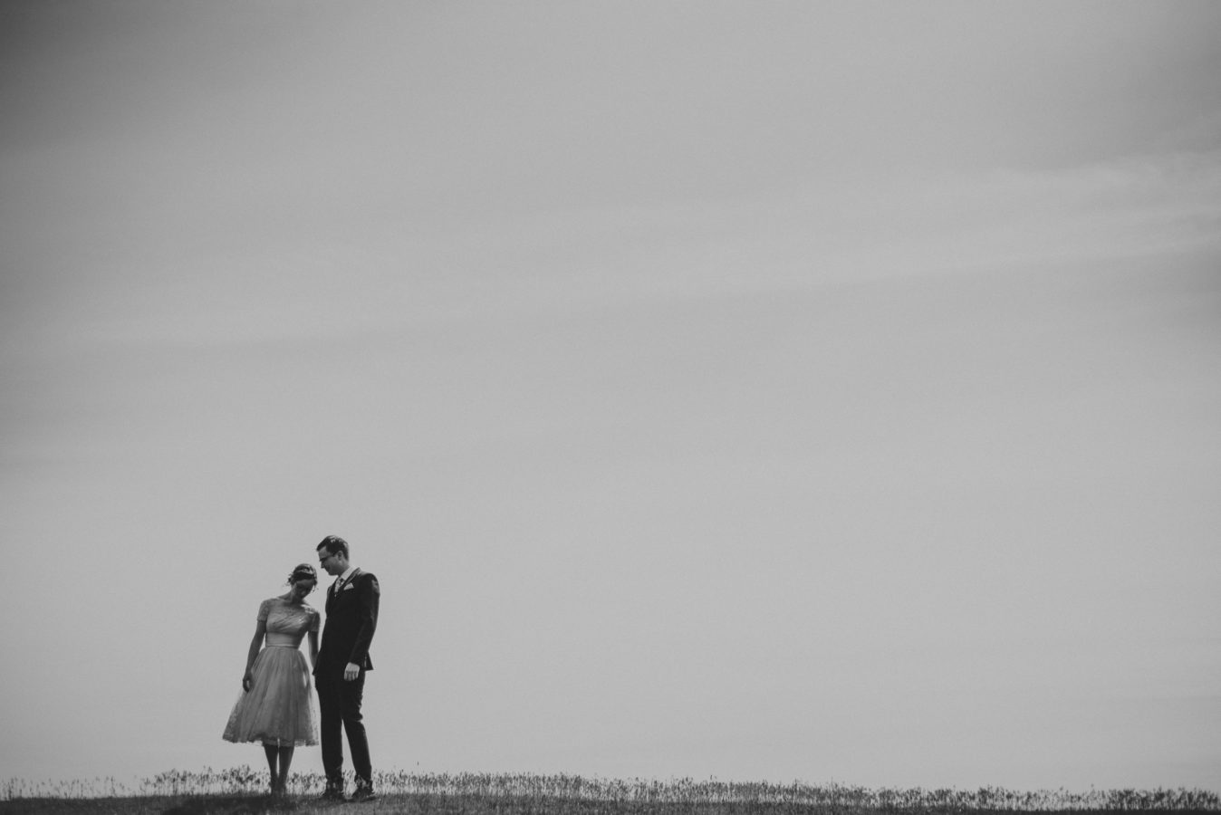 bride and groom leaning in on one another with a huge sky framing them