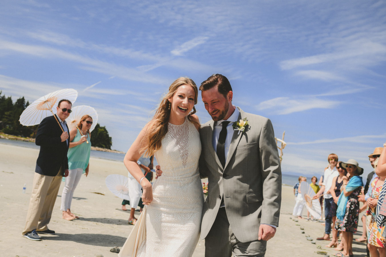 bride and groom walking up the aisle smiling and hugging after their beach wedding ceremony