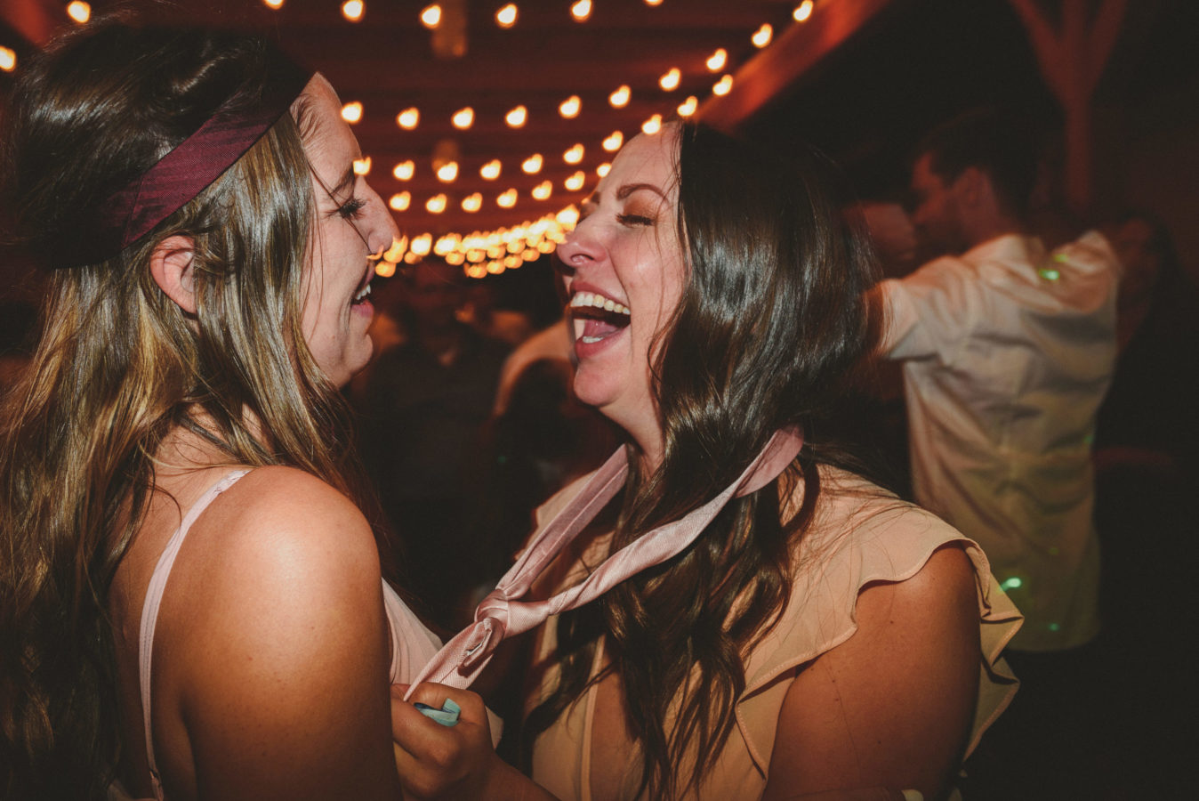 two bridesmaids laughing on the dance floor at a wedding