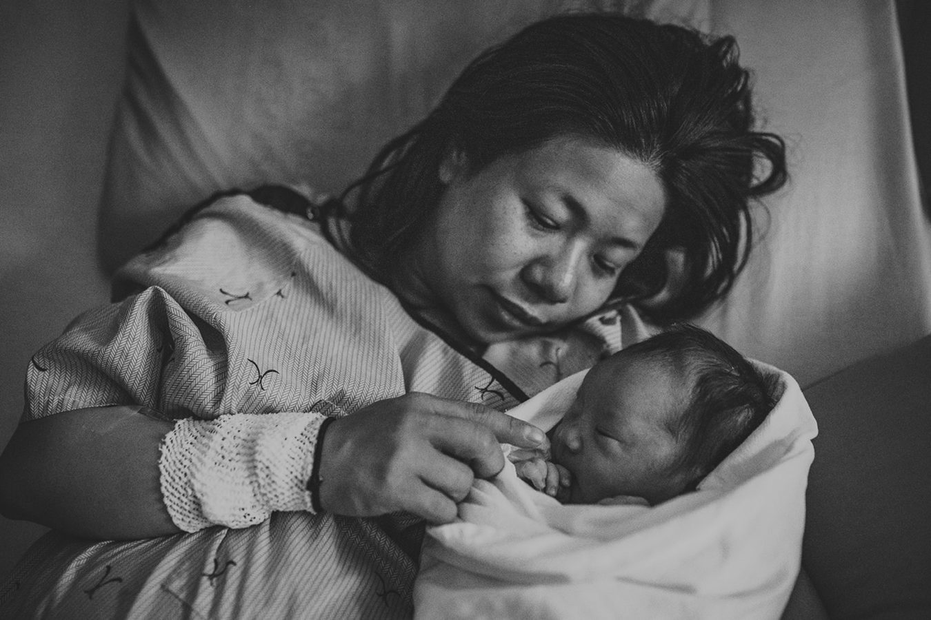 mom snuggling her newborn baby in her hospital bed post-labour