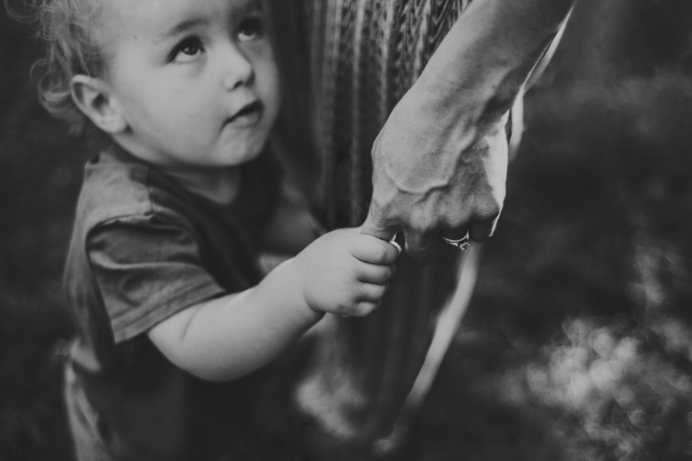 looking down on a child looking up at his mom while holding her finger