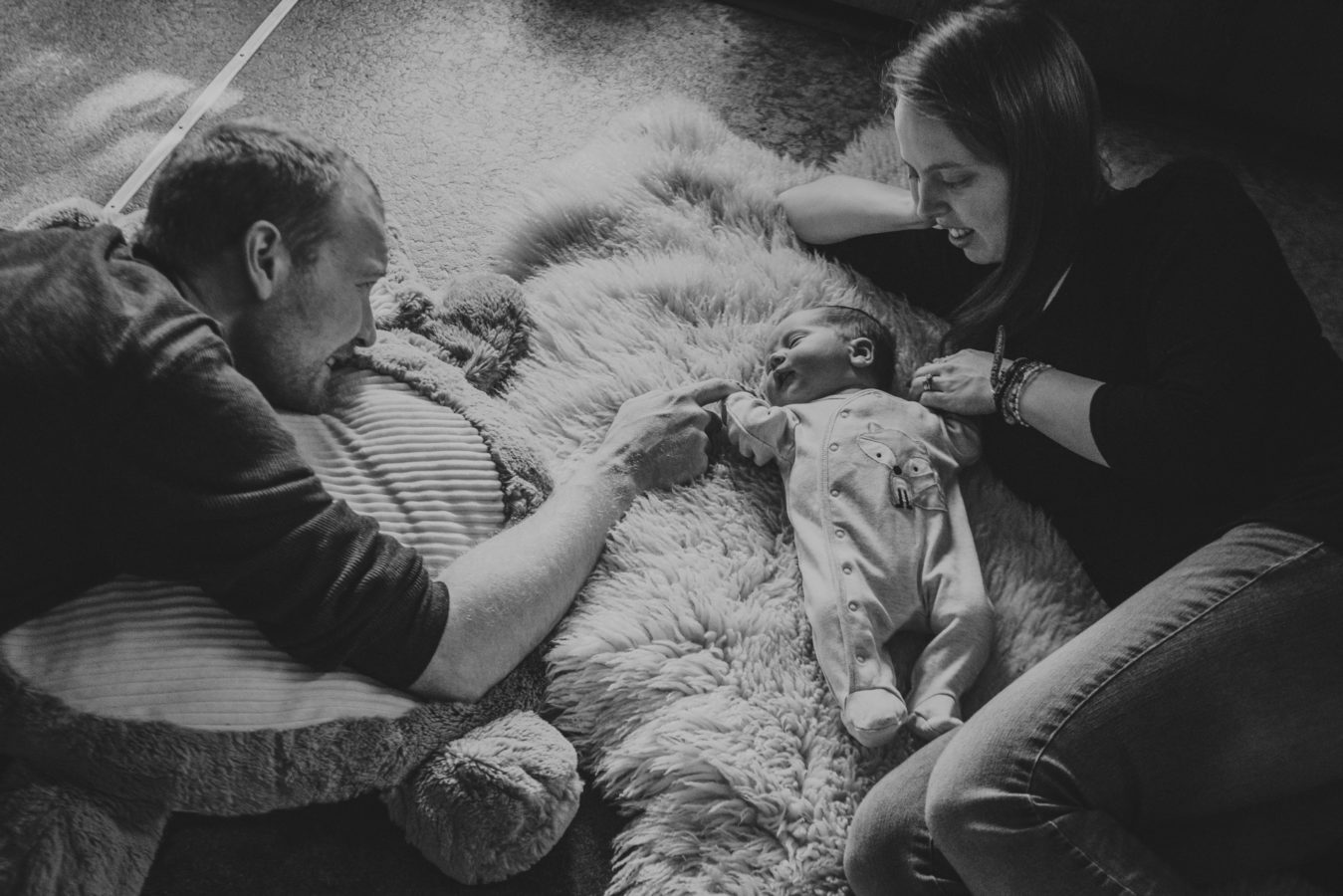 looking down on a mom, dad and baby lying on the floor together