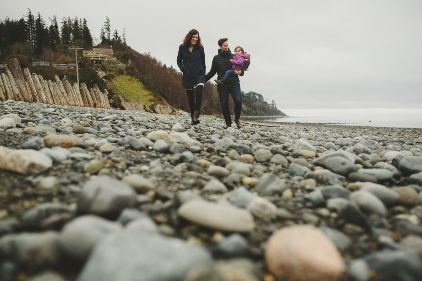 two moms and their kid walking down a rocky beach