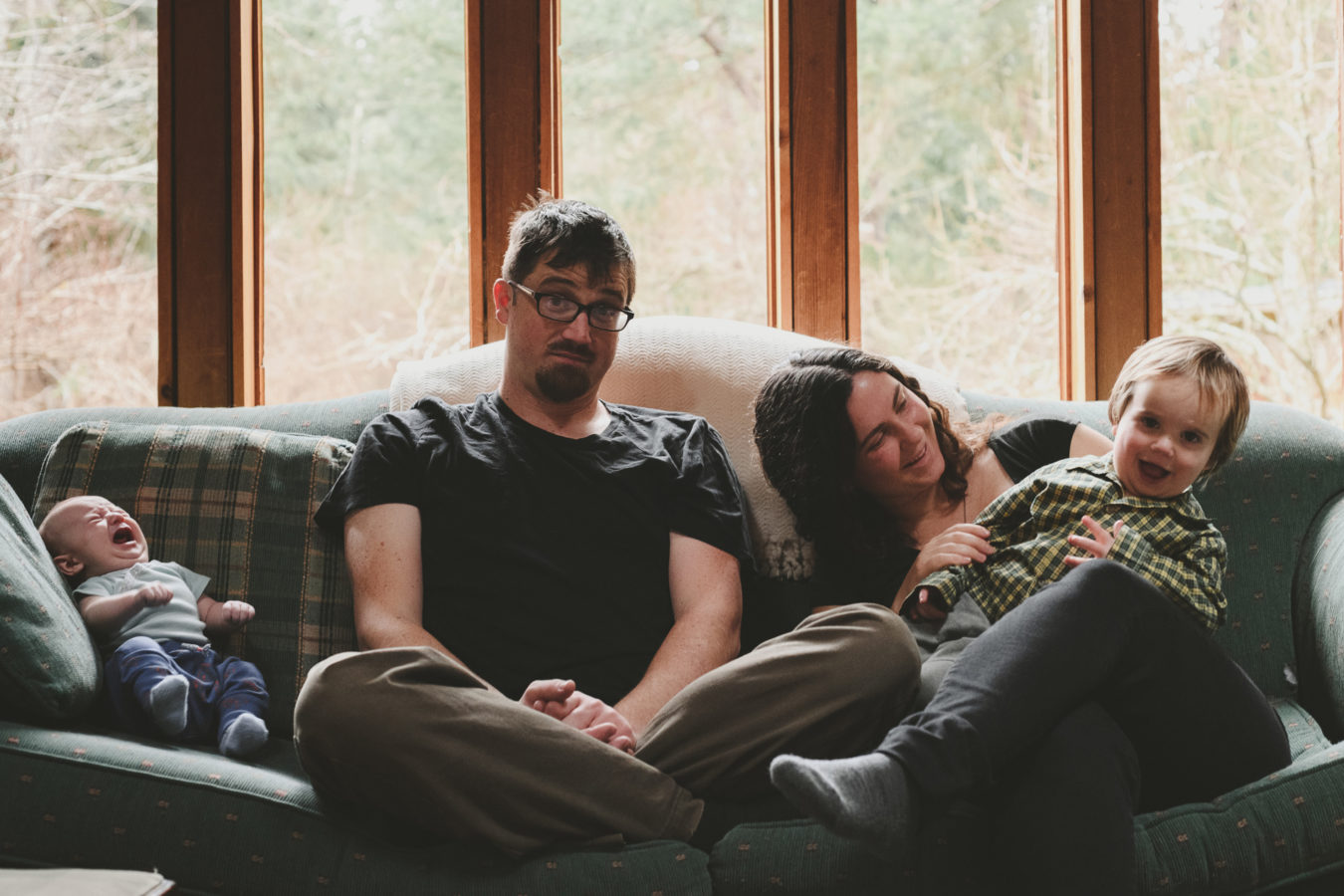 funny photo of a mom, dad, baby and kid on their couch