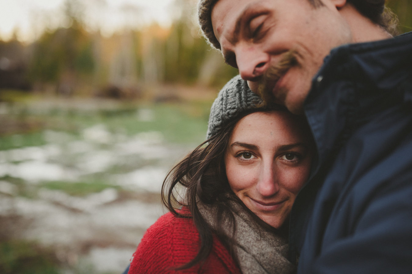young woman snuggled into her man smiling at the camera