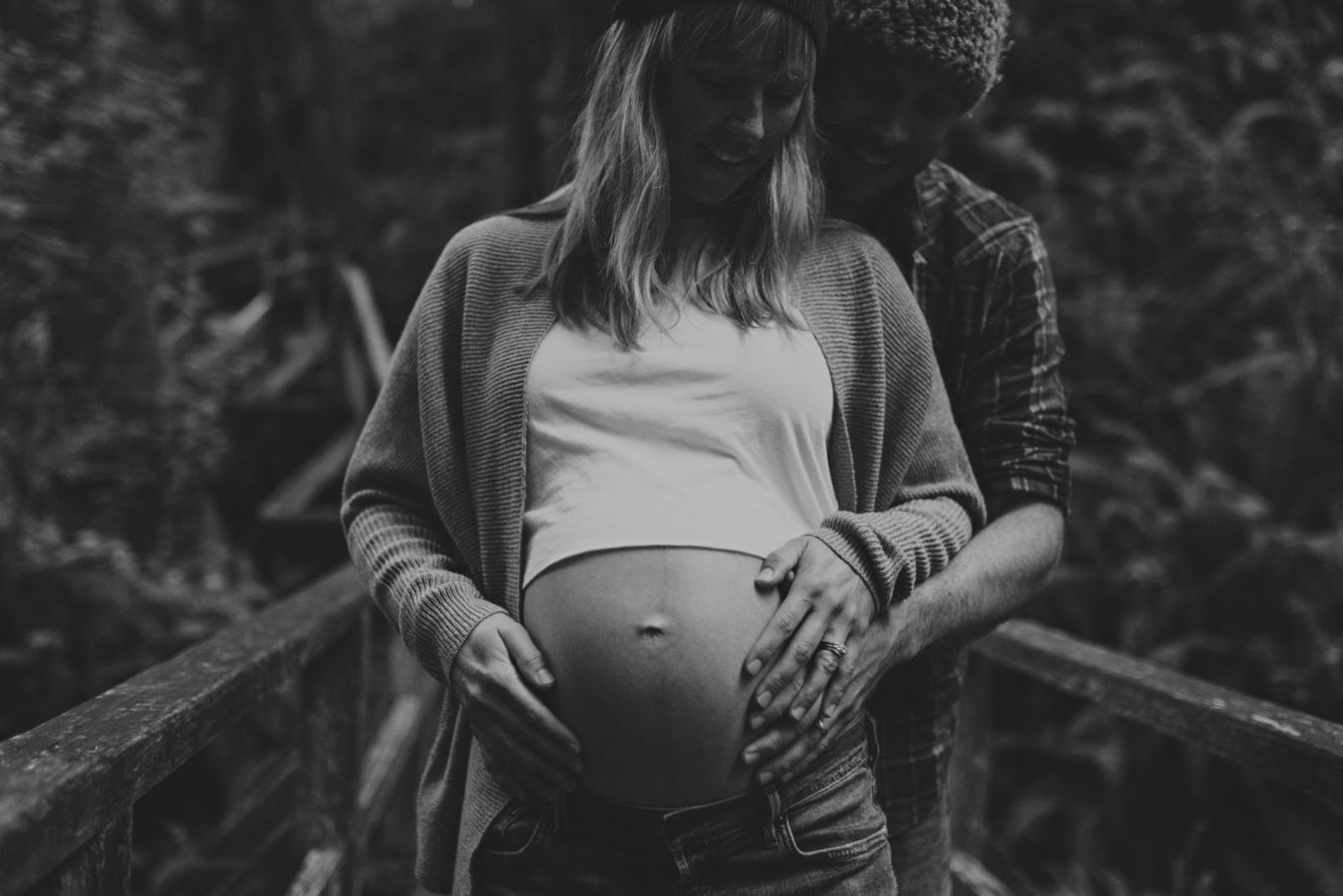 close up of a pregnant woman's belly with her & her partner's hands holding her belly