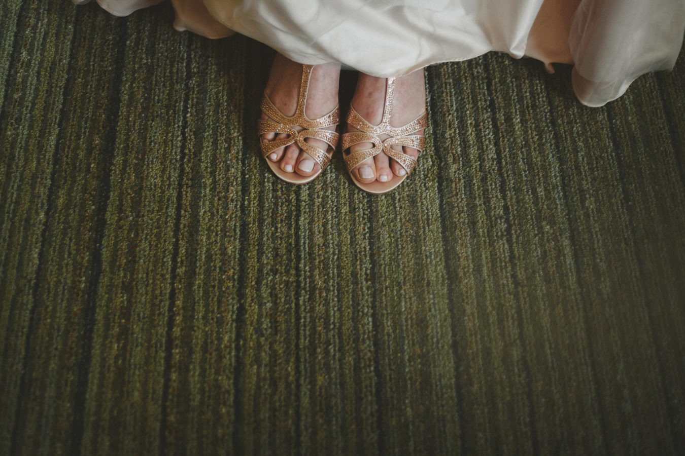 detail looking down on bride's wedding shoes & edge of her wedding dress