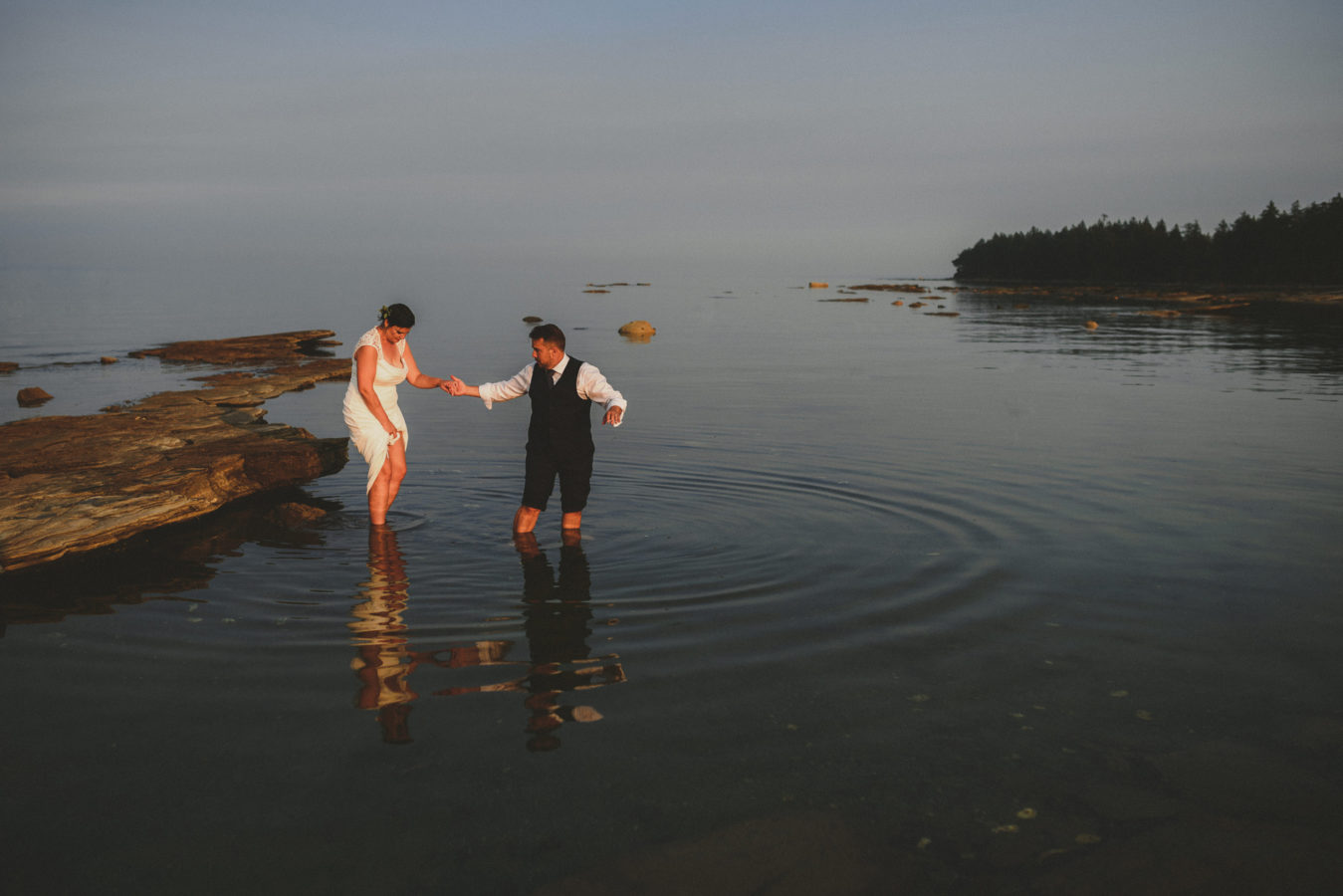 an older bride and groom wading in the ocean on their wedding day