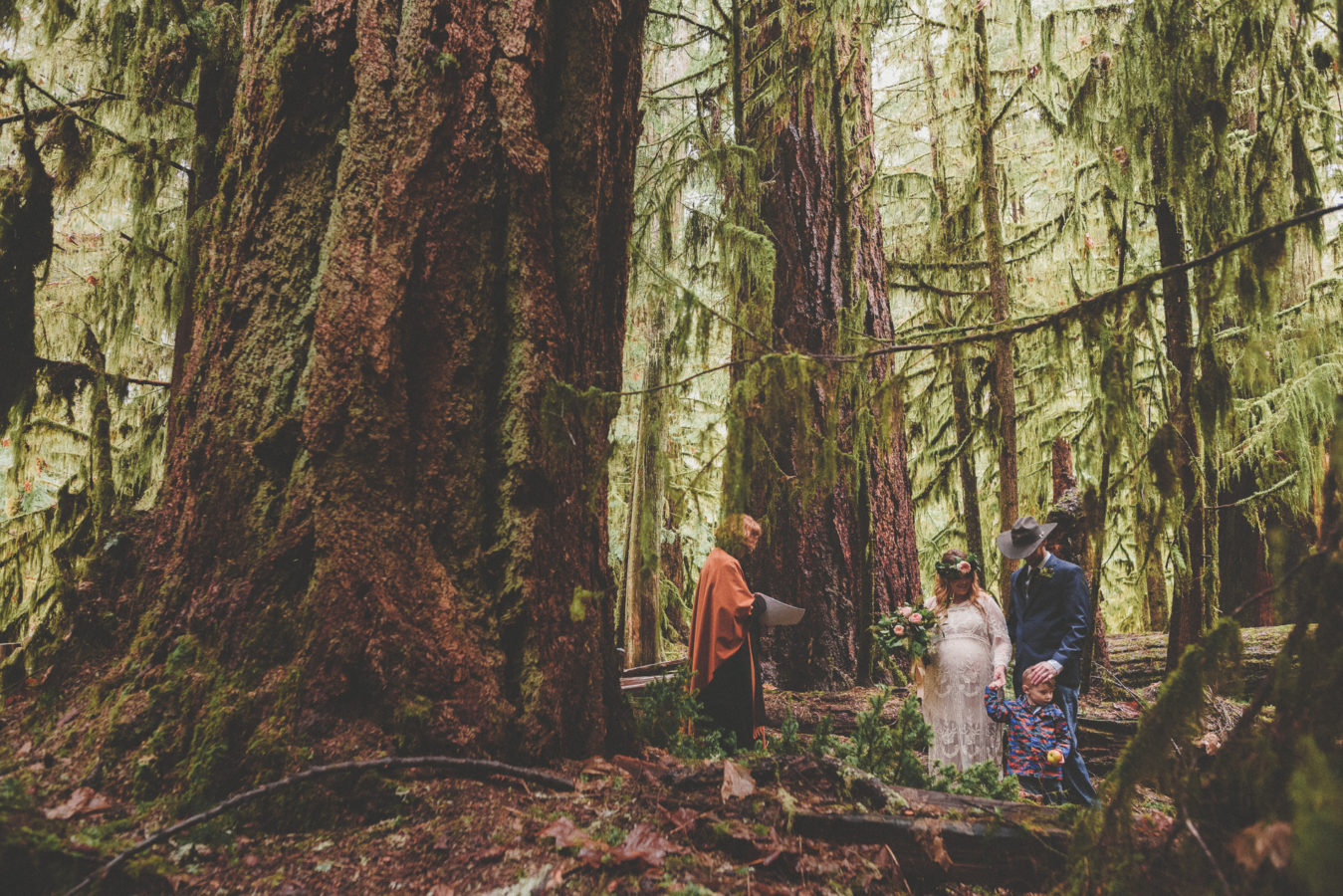 bride, groom, their young son and officiant getting married in the old growth forest