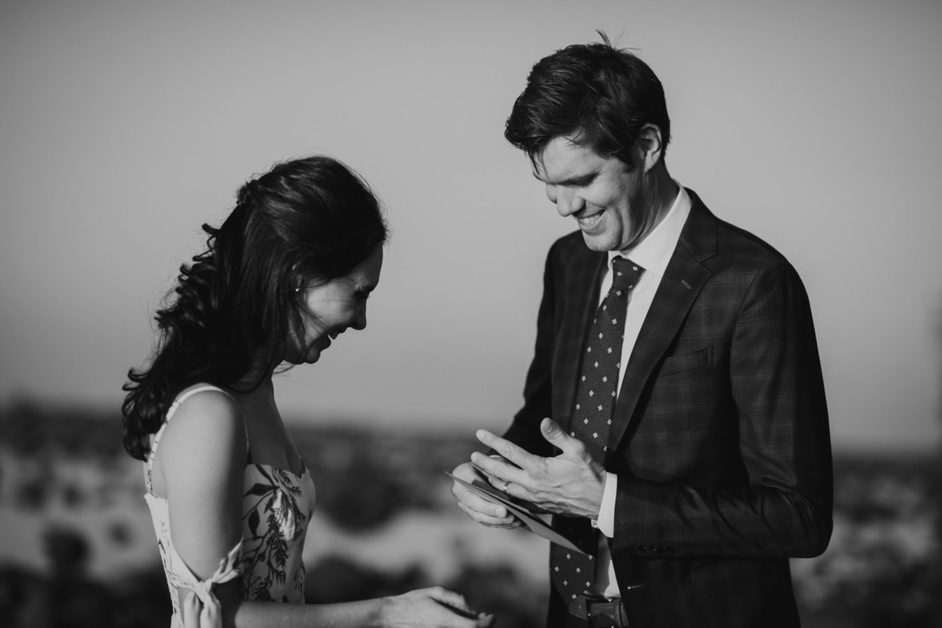 bride and groom laughing at their elopement as he tries to get his ring on his finger