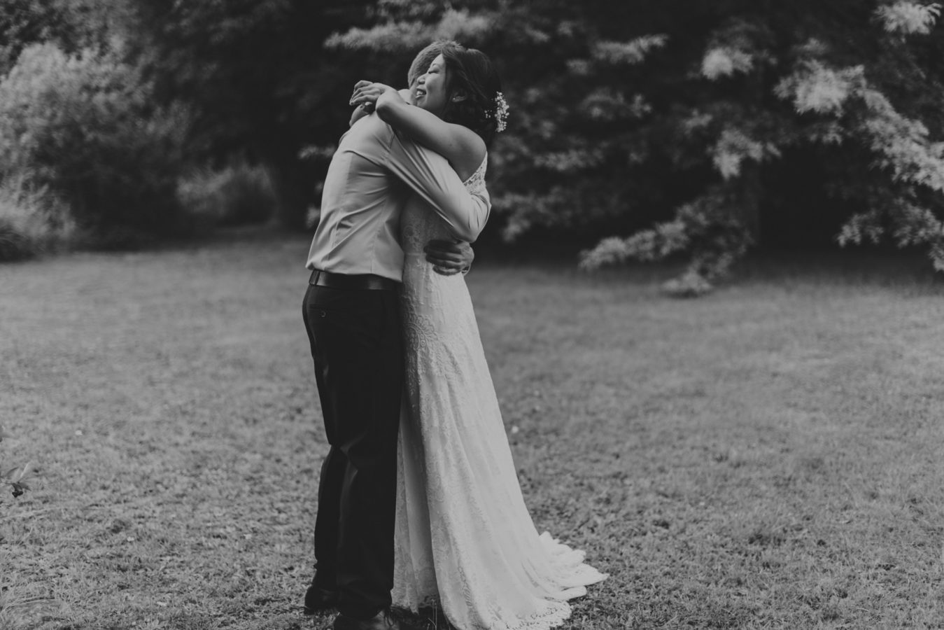 mixed race couple hugging on their wedding day with the forest behind them