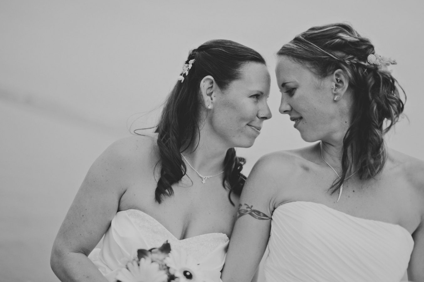 two brides in wedding dresses intimately looking at one another