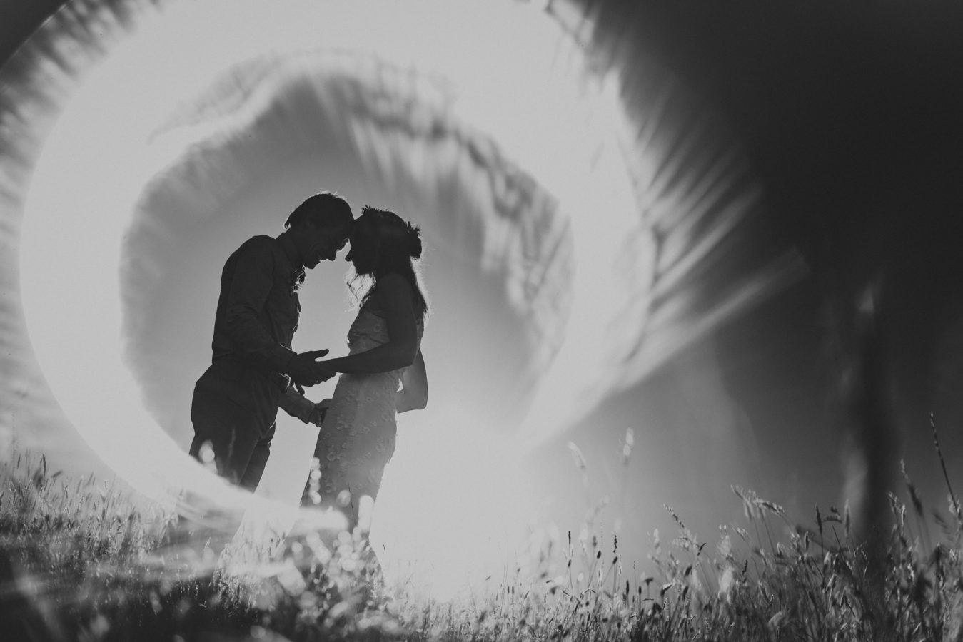 bride and groom holding hands in a grassy field with a ring of light surrounding them