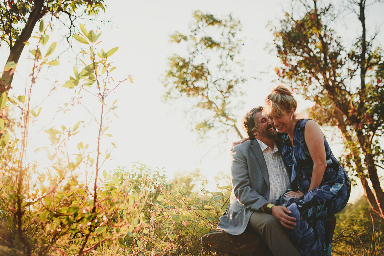 older couple sitting in the sunset laughing