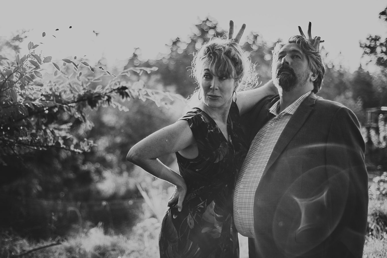 older couple looking serious while they put bunny ears behind each other's heads